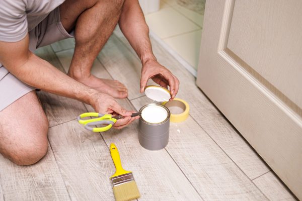 Opening a can of paint with a pair of scissors. Repair staining the doors with paint.