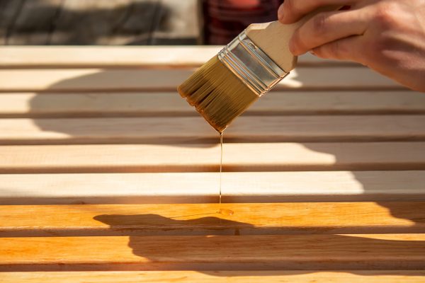 Painting wooden furniture with varnish. a man hides a tree with varnish. Selective focus